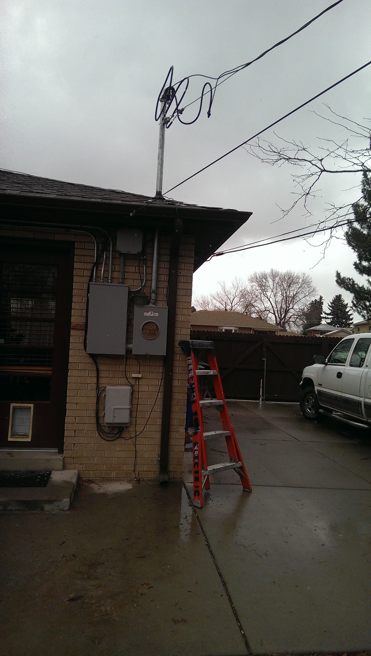 Brick house with a new service mast, meter and panel, a red ladder against the wall